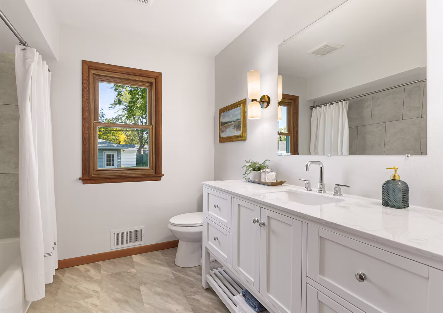 Bright white double vanity bathroom with shower/tub combo and natural light