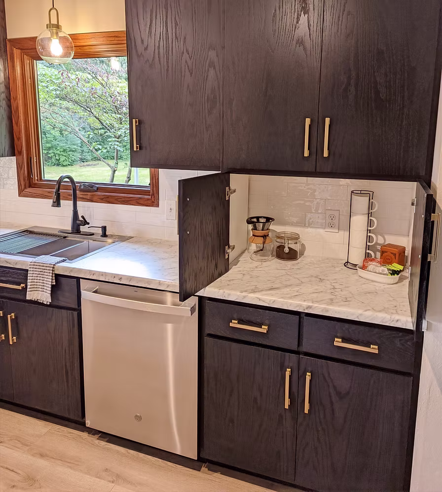 Dark kitchen cabinets with marble backsplash, gold hardware, and white quartz countertops