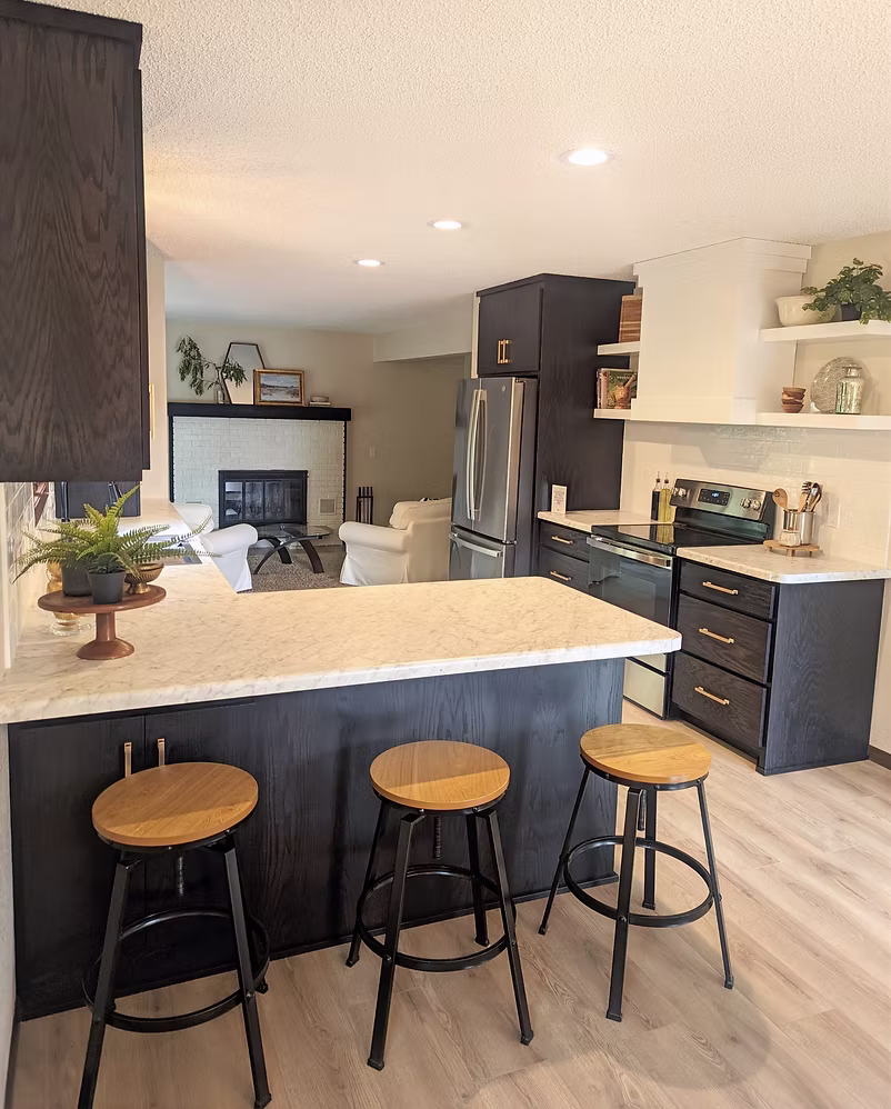 Dark navy kitchen with large white quartz island and upholstered bar stools
