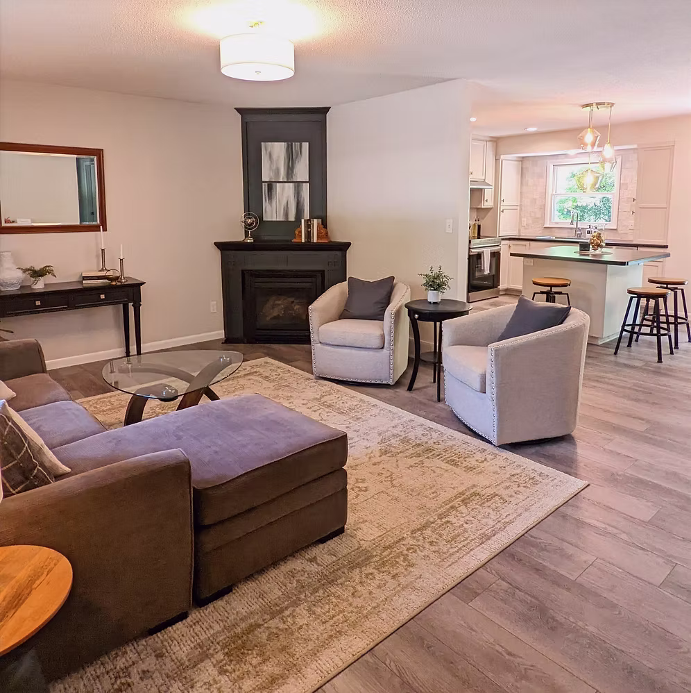 Living room with sectional sofa, fireplace, area rug, and kitchen beyond