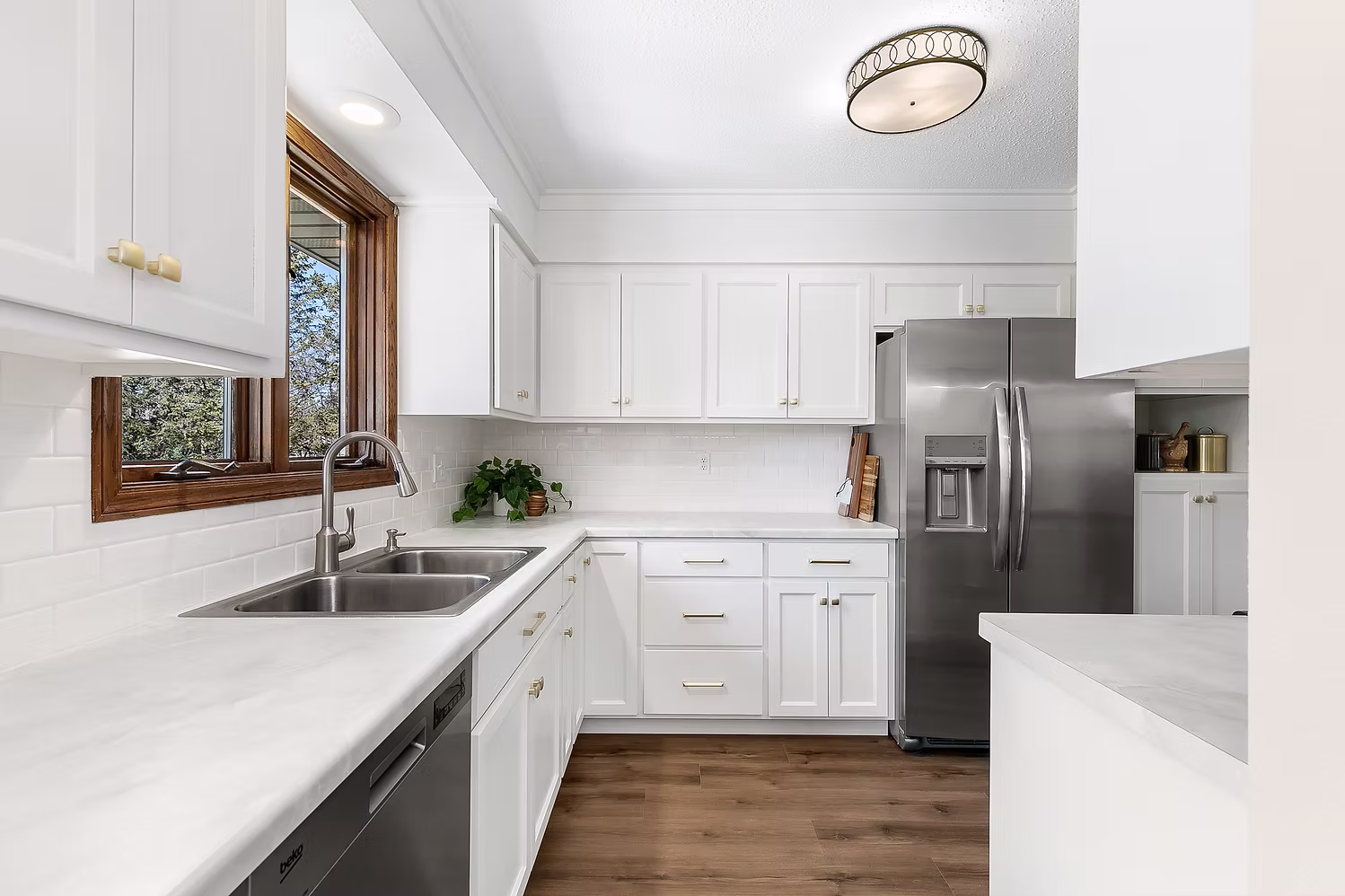 White kitchen with dark hardwood floors, stainless appliances, and farmhouse sink