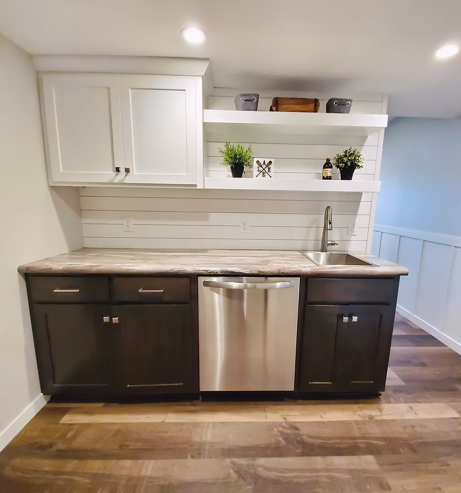 Basement wet bar with white upper and dark lower cabinets and open shelving