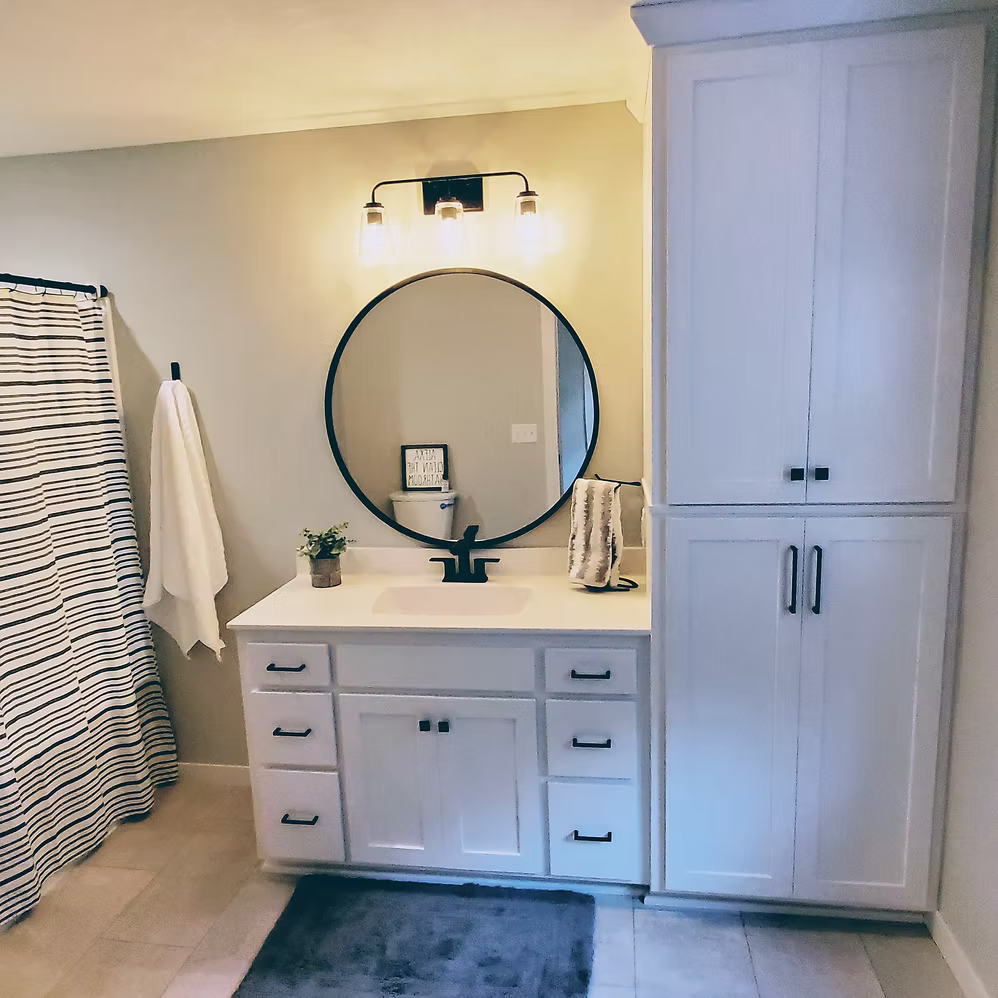 White bathroom with gray vanity, round mirror, and striped shower curtain