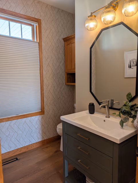 Celebration half bath with a dark green vanity and statement wallpaper