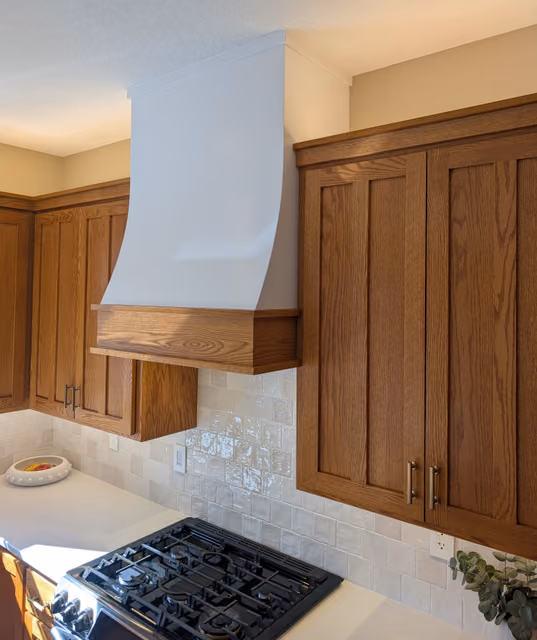 Celebration kitchen hood with a gentle slope and trim that coordinates with the cabinetry crown moulding