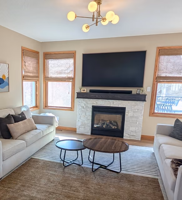 Celebration living room with a stone-wrapped fireplace, a custom sliding mantle, and a modern light fixture